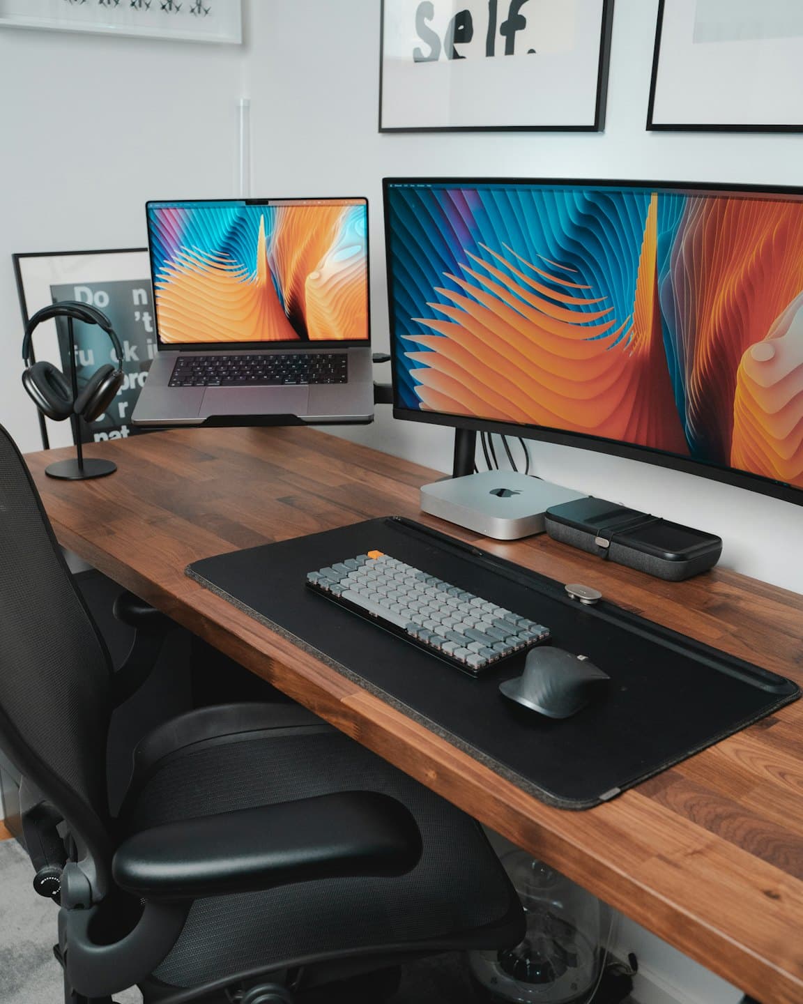 Laptop and curved monitor sit on a tidy wooden desk.
