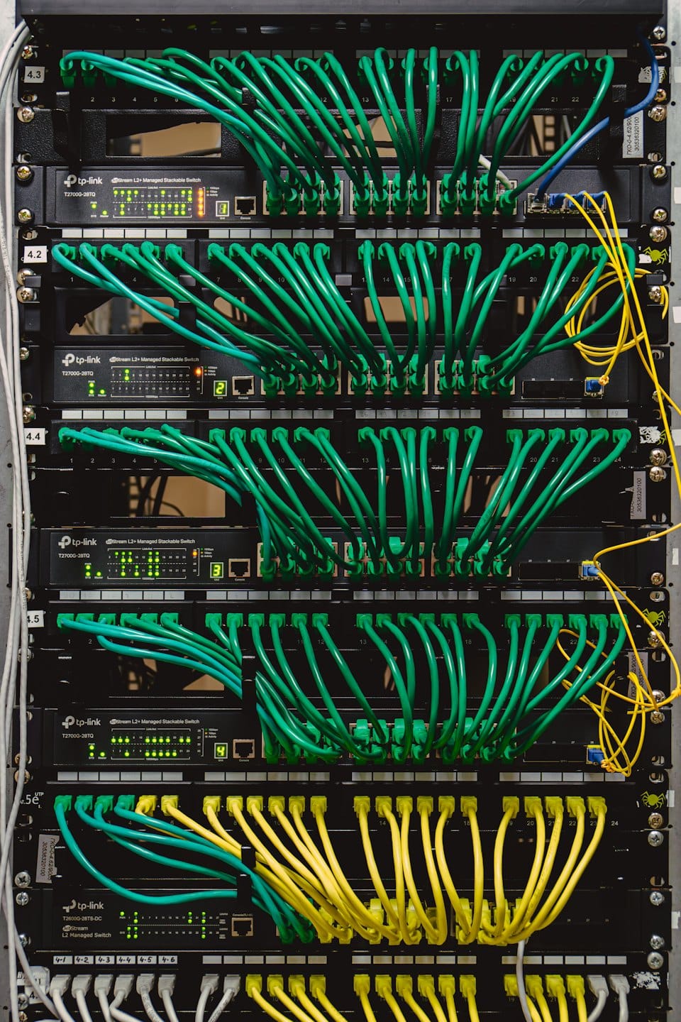 Stacked network switches with many plugged-in ethernet cables.