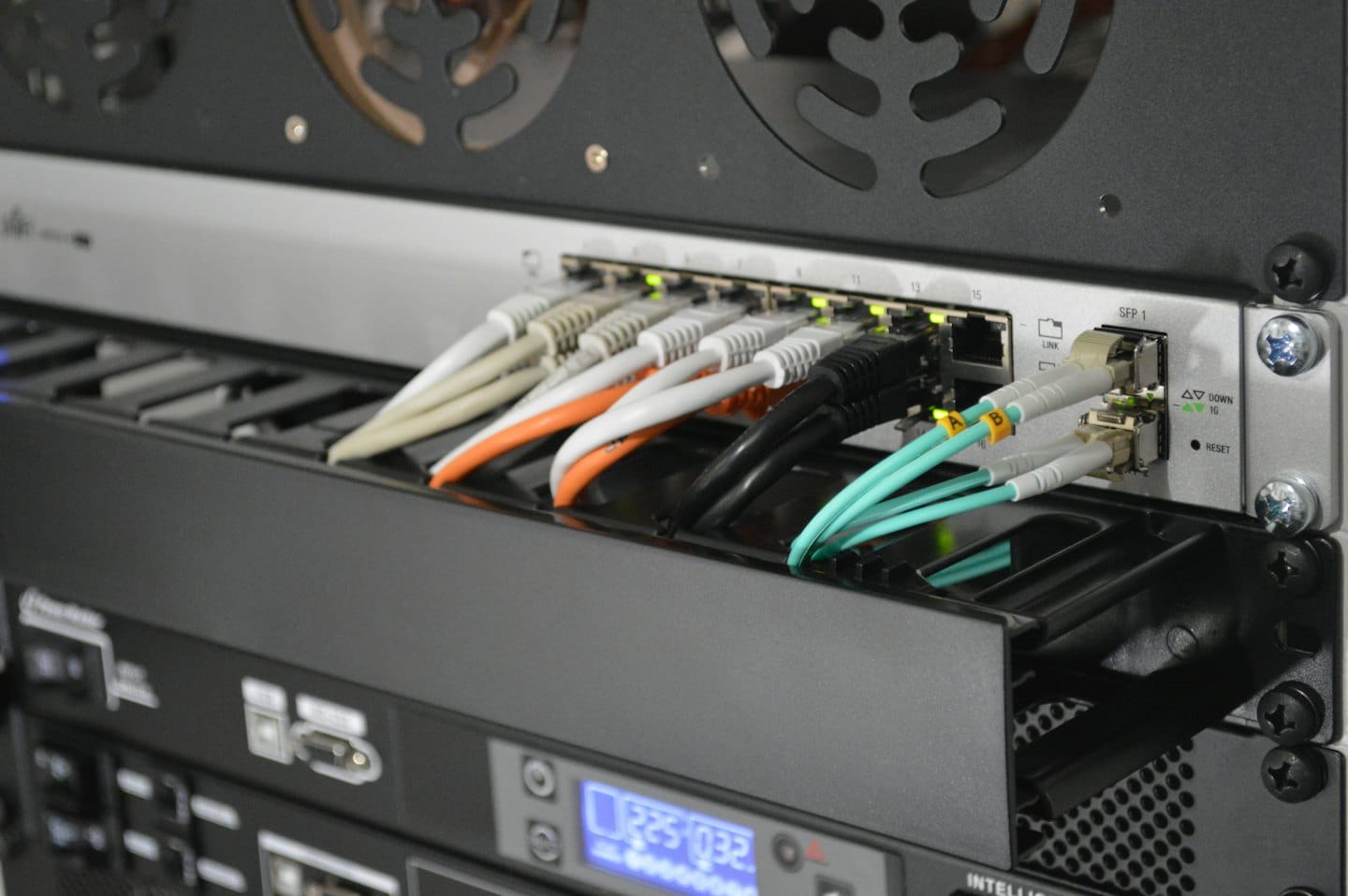 Network switch in a server rack with many cables plugged in.